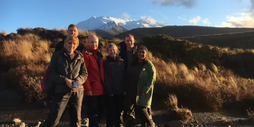 Group of walkers posing on the Taranaki Falls Track with Mount Ruapehu in the background