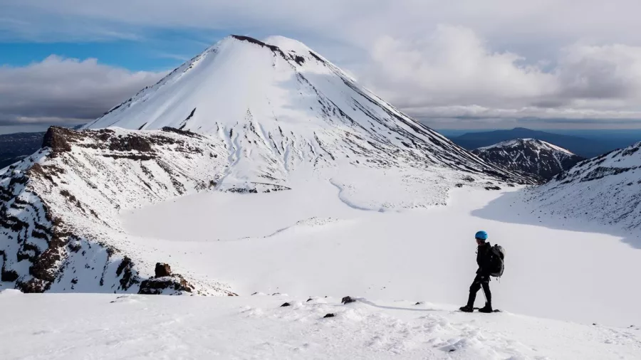 Hiker snowshoeing across snowy terrain near Mount Ngauruhoe