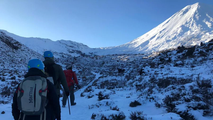Guided hikers in snow with Mount Ngauruhoe on the Tongariro Alpine Crossing