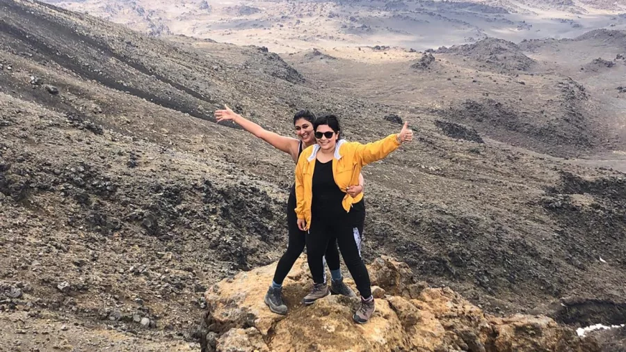 Two women celebrating on a rock along the Tongariro Alpine Crossing