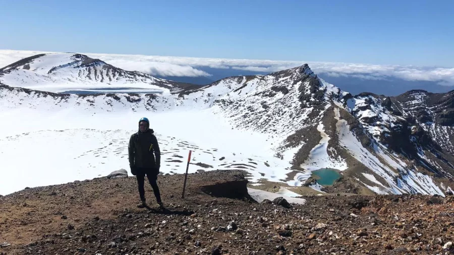 Hiker standing by the snowy crater and lakes on the Tongariro Alpine Crossing