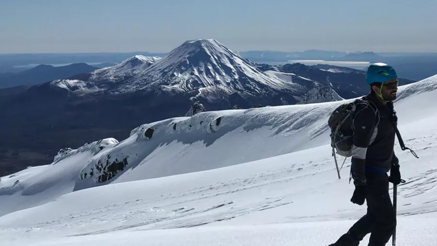 Climber on snowy Ruapehu ridgeline looking towards Mount Ngauruhoe in the distance