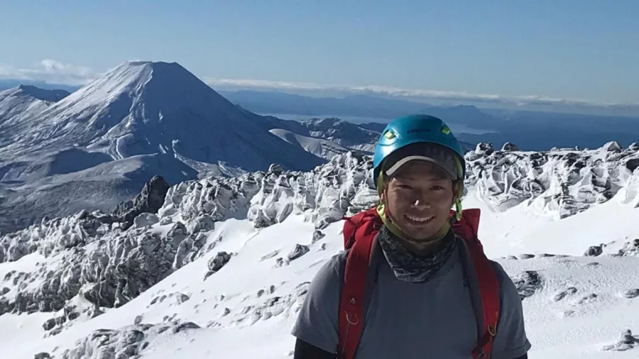 Male hiker on snowy Mt Ruapehu with Mount Ngauruhoe and rugged volcanic ridges in the background