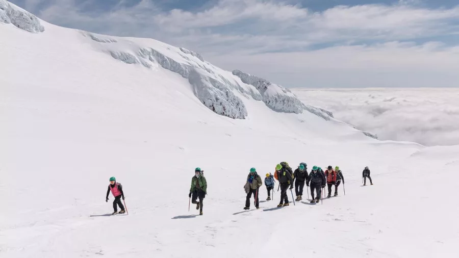 Guided group using crampons and ice axes to climb snow slopes on Mount Ruapehu