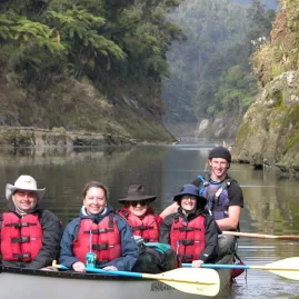 Family and guide smiling in a canoe on the Whanganui River during a guided tour