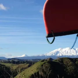 Red canoe on a roof rack with Mount Ruapehu and Tongariro landscape in the distance