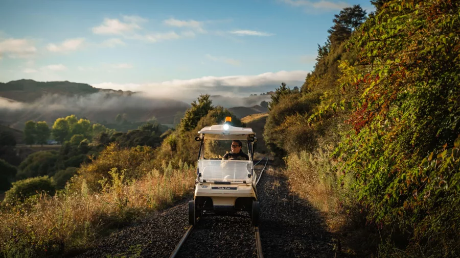 Rail cart travelling through a misty valley at sunrise on the Forgotten World Expedition.