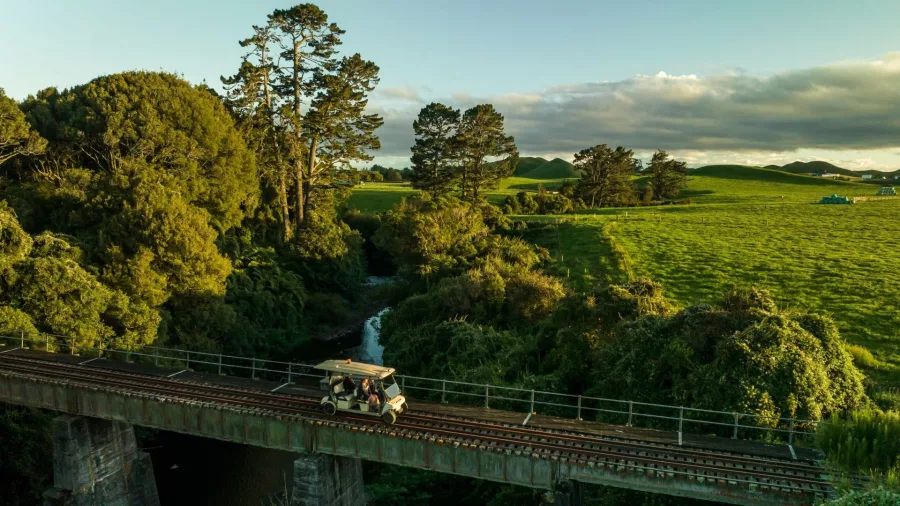 Rail cart crossing a bridge over a stream during golden hour on the Forgotten World Adventures route.