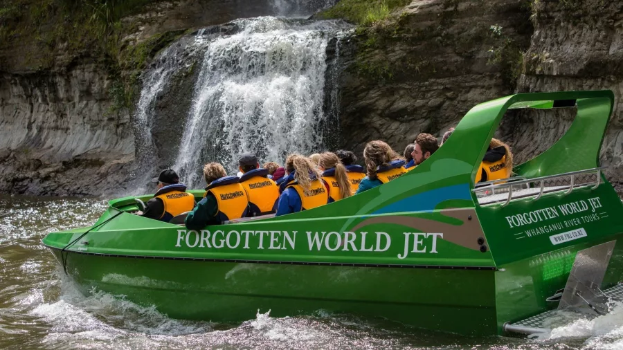 Forgotten World Jet boat cruising toward a scenic waterfall on the Whanganui River.