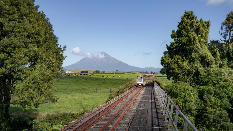 Rail cart crossing a bridge with Mount Taranaki in the distance on the Forgotten World Adventures tour.