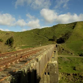 Rustic railway bridge stretching through rolling green hills on the Forgotten World Adventures rail route.