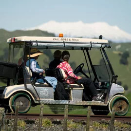 Travellers in a Forgotten World Adventures rail cart with Mount Ruapehu in the background on a clear day.
