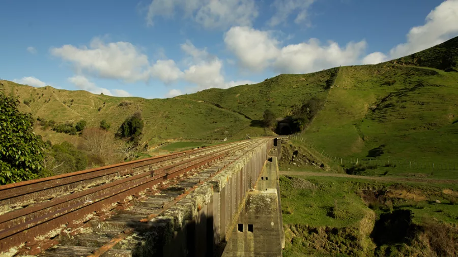Rustic railway bridge stretching through rolling green hills on the Forgotten World Adventures rail route.