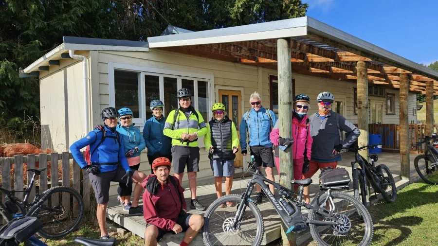 Group of smiling cyclists with their E-bikes outside River Valley base lodge
