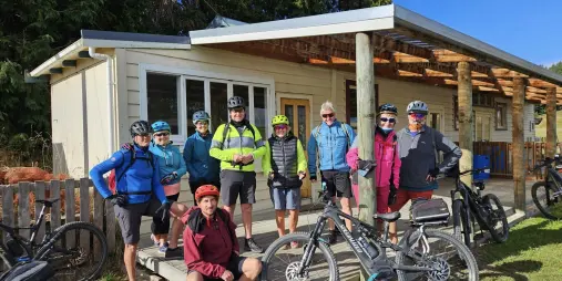 Group of smiling cyclists with their E-bikes outside River Valley base lodge