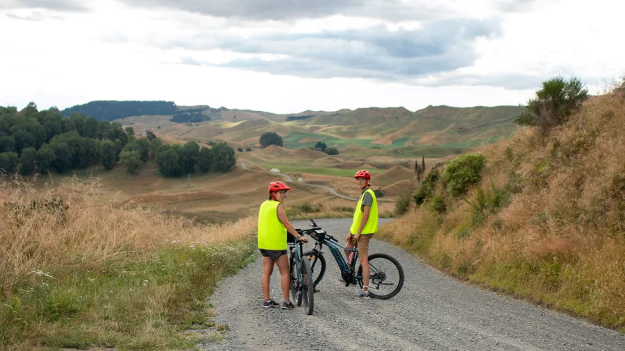 Two cyclists on a gravel backroad surrounded by rolling hills near River Valley
