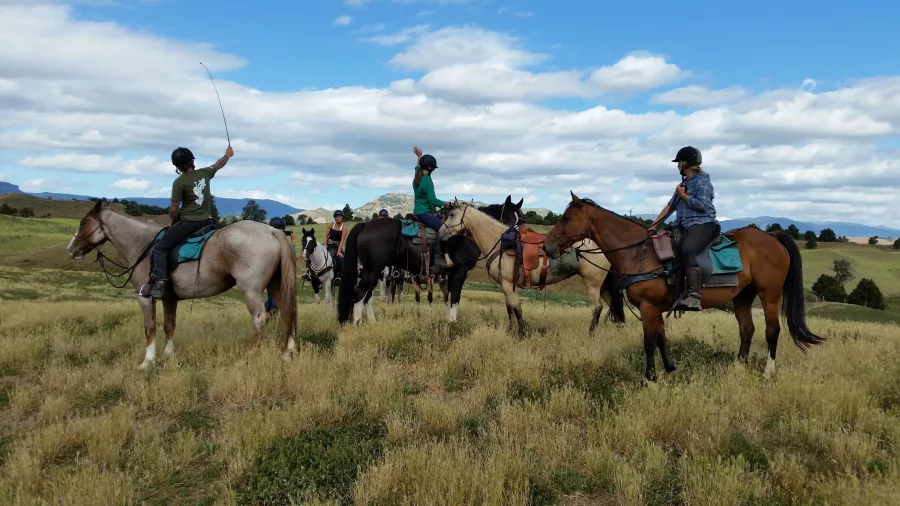 Group of riders taking a break on a golden hilltop trail with wide open views
