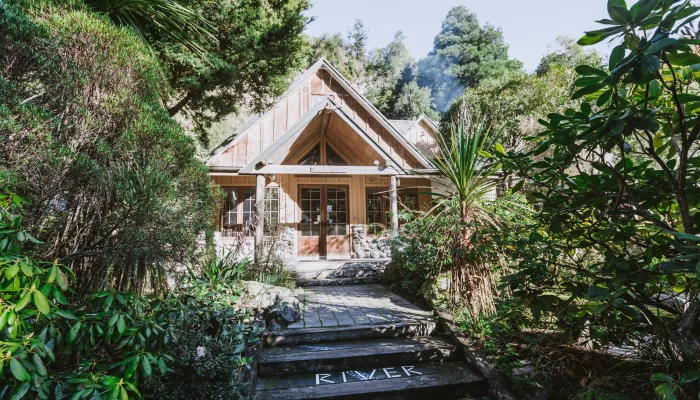 Wooden lodge entrance surrounded by lush green bush at River Valley