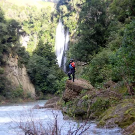 Rafting guide standing near remote Rangitikei waterfall with whitewater in foreground