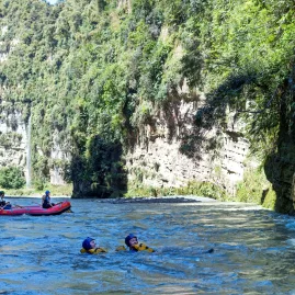 Rafters and swimmers floating through a sunny gorge on the Rangitikei River