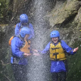 Children in rafting gear enjoying a waterfall shower on the Rangitikei River