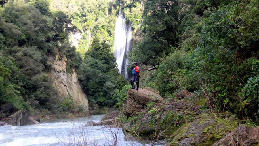 Rafting guide standing near remote Rangitikei waterfall with whitewater in foreground