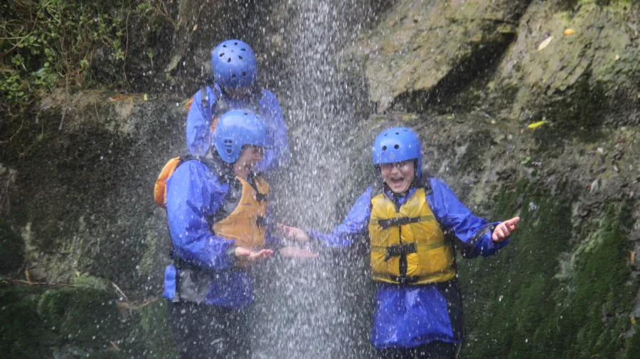 Children in rafting gear enjoying a waterfall shower on the Rangitikei River