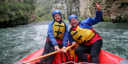 Father and daughter smiling in raft with Rangitikei Gorge cliffs behind