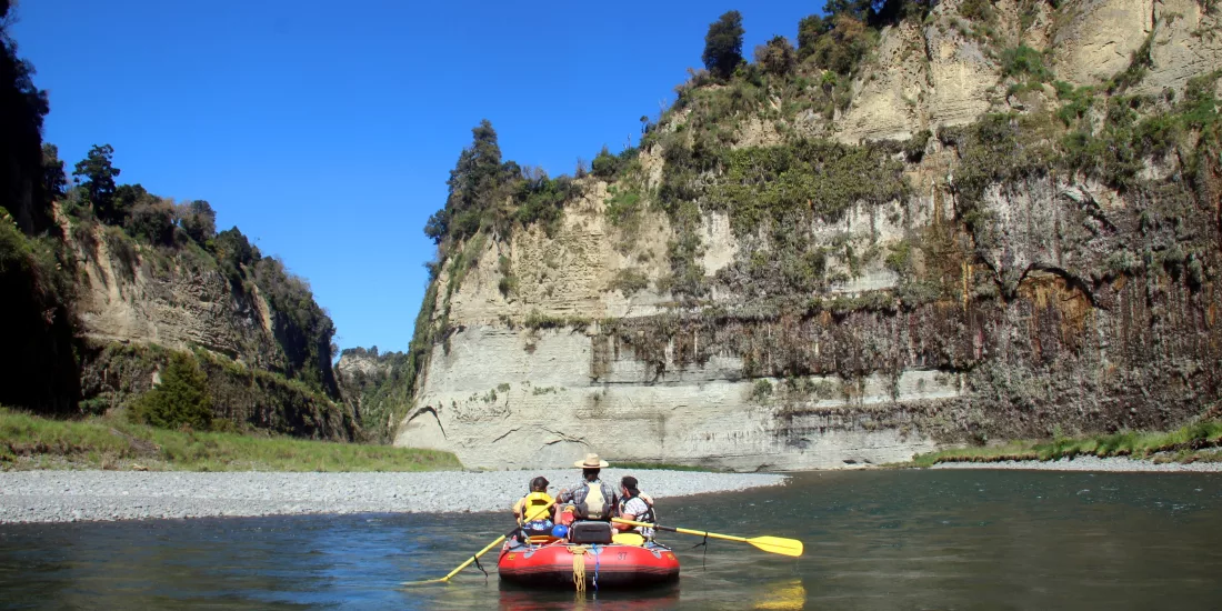 Group rafting through a wide scenic section of the Rangitikei River