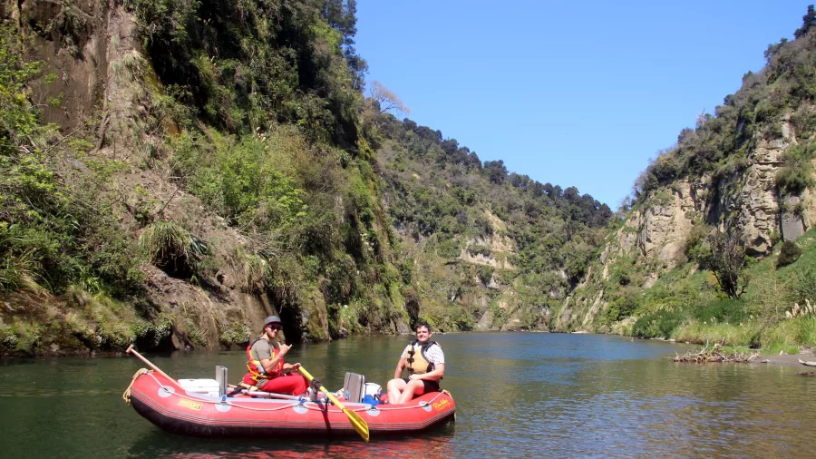 Two paddlers floating calmly through a scenic canyon on a gear raft