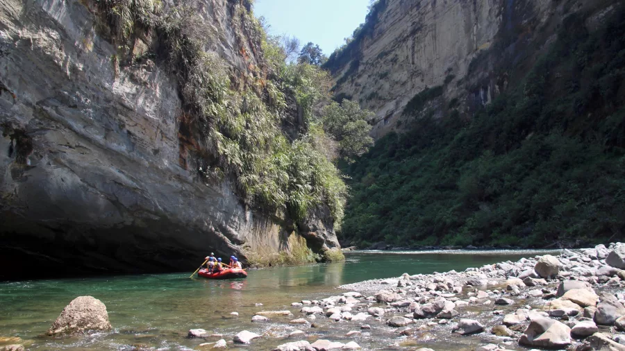 Raft passing under overhanging cliffs in a narrow Rangitikei River gorge