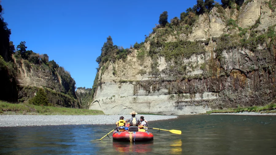 Group rafting through a wide scenic section of the Rangitikei River