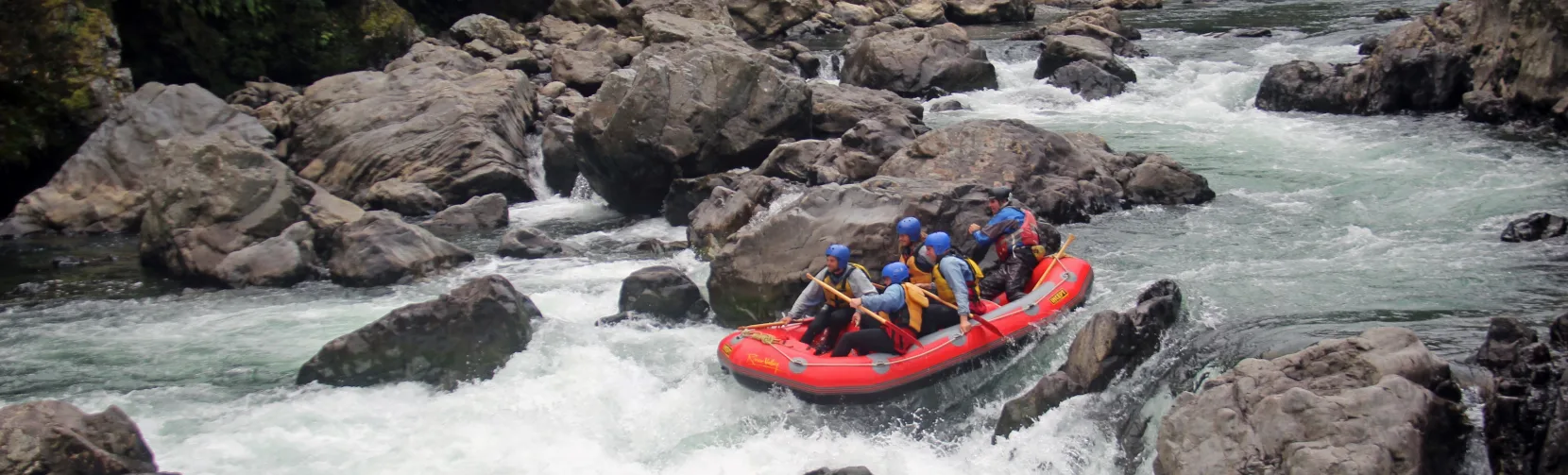 Raft navigating between large boulders on the Rangitikei River white water section