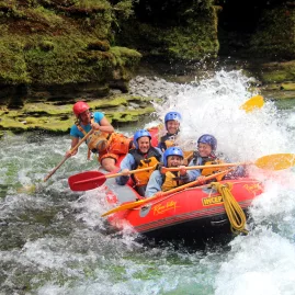 Rafters surf a standing wave in The Narrows on the Rangitikei River, surrounded by steep gorge walls