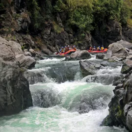 Raft poised above the turbulent entry to See Thru rapid in the Rangitikei Gorge, surrounded by rugged canyon walls and powerful whitewater