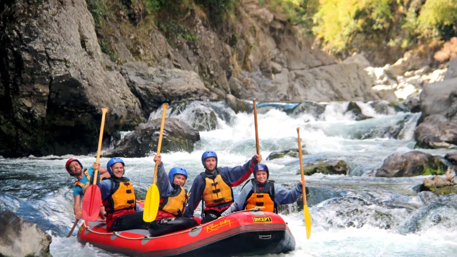 Rafting team celebrating with raised paddles after completing a series of rapids on the Rangitikei River