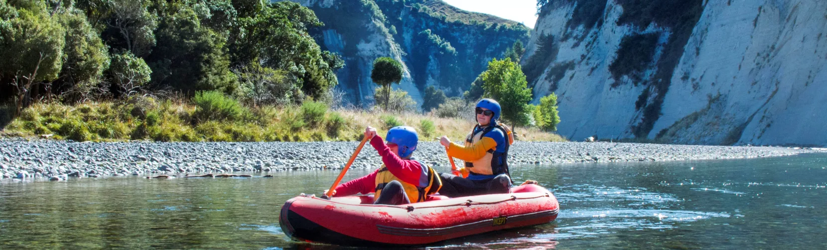 Parent and child paddling together in an inflatable kayak through calm Rangitikei waters
