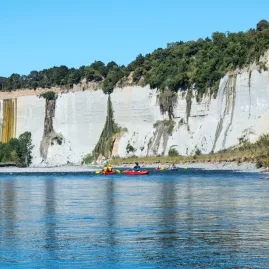 Inflatable kayaks on the Rangitikei River with white papa cliffs and a waterfall in the background