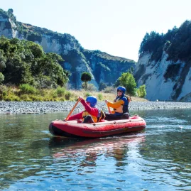 Parent and child paddling together in an inflatable kayak through calm Rangitikei waters