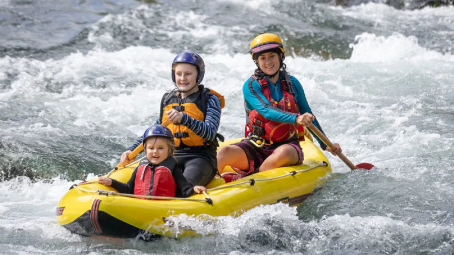 Family of three navigating gentle whitewater in a yellow duckie on the Rangitikei River