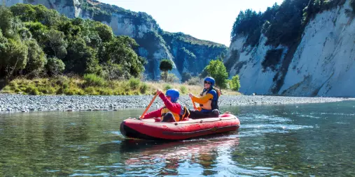 Parent and child paddling together in an inflatable kayak through calm Rangitikei waters