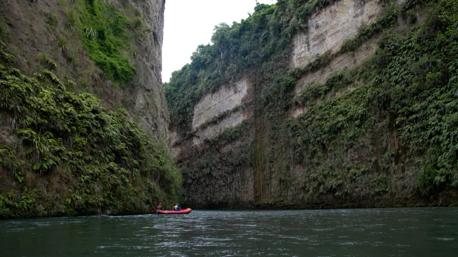 Raft gliding between towering fern-covered limestone cliffs on the Rangitikei River