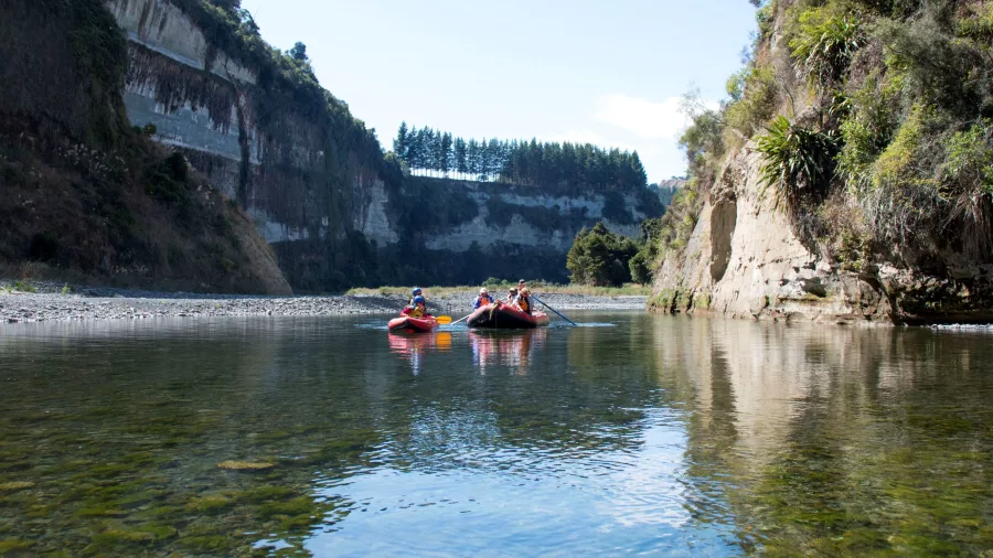 Rafters floating past layered canyon walls and pine trees in Mokai Canyon