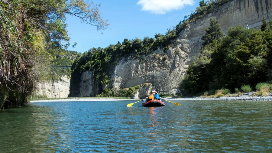 Raft on the Rangitikei River approaching Mokai Canyon with a suspension bridge in the distance