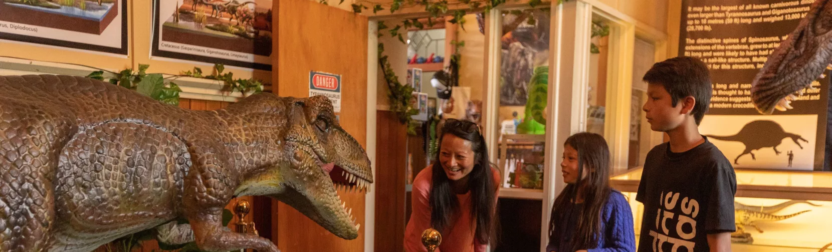 Family looking at a large dinosaur model at Dinosaur House in Raetihi
