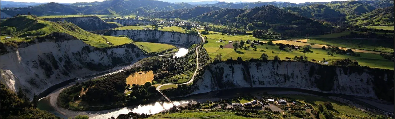 Aerial view of Mangaweka’s scenic white cliffs and the Rangitīkei River with Awastone Campground surrounded by green hills in Manawatū, New Zealand