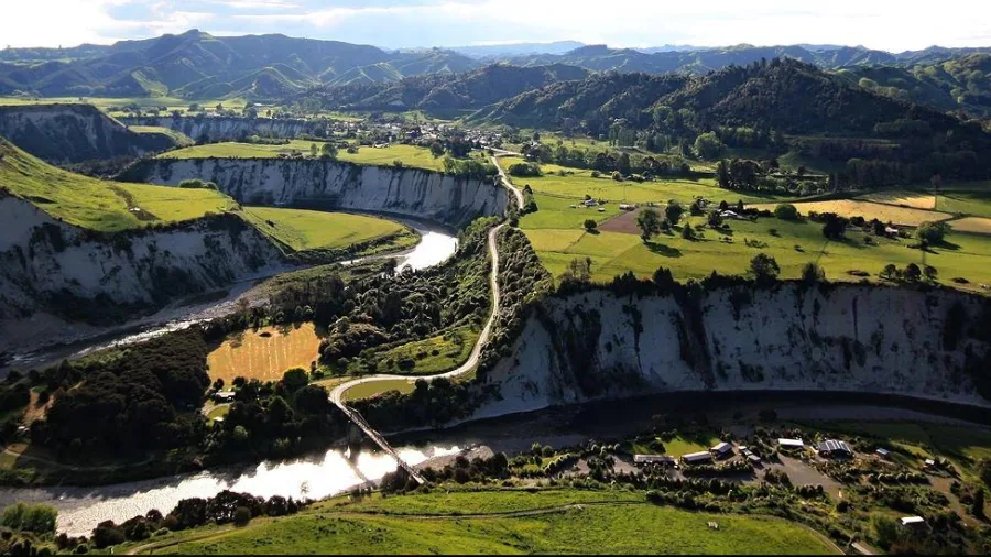 Aerial view of Mangaweka’s scenic white cliffs and the Rangitīkei River with Awastone Campground surrounded by green hills in Manawatū, New Zealand