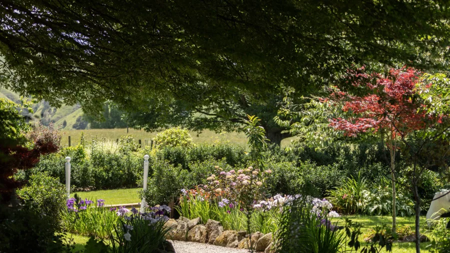 Shaded garden path surrounded by flowers at Omaka Lodge in Taumarunui
