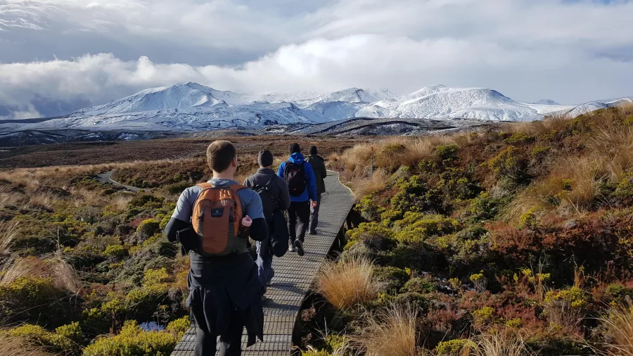 Group hiking the Tongariro Alpine Crossing along boardwalk in winter