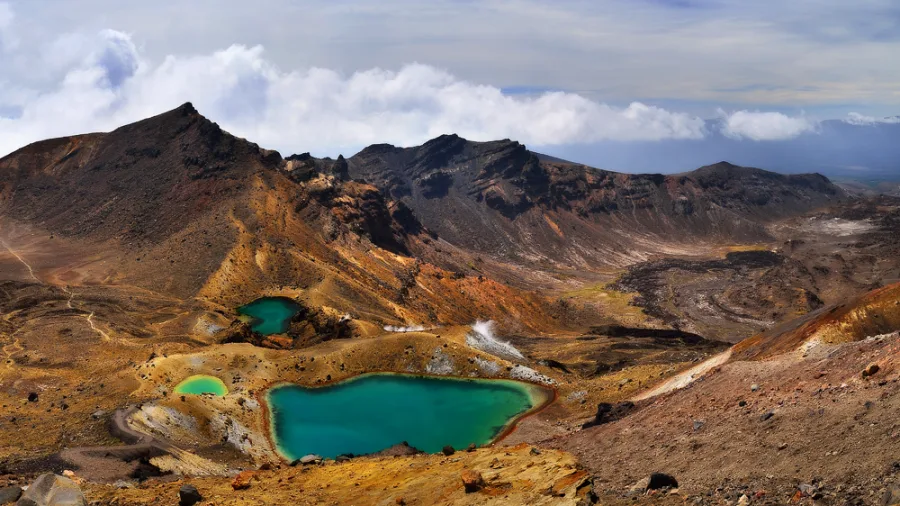 Panoramic view of the Emerald Lakes surrounded by volcanic mountains on the Tongariro Alpine Crossing in New Zealand.
